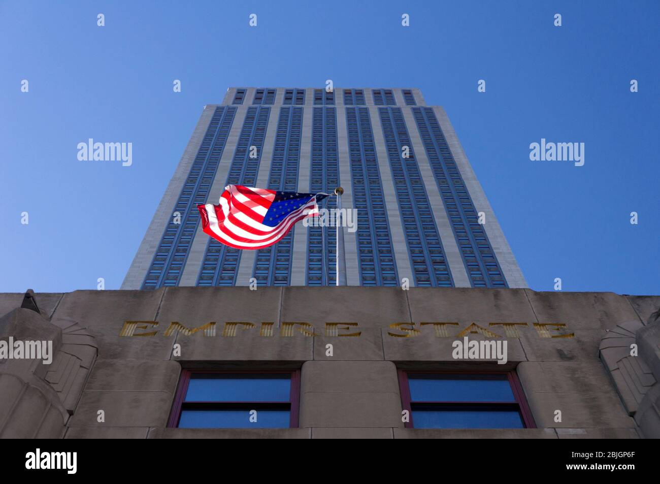 Guardando direttamente lo storico Empire state Building con la bandiera americana a New York City Foto Stock