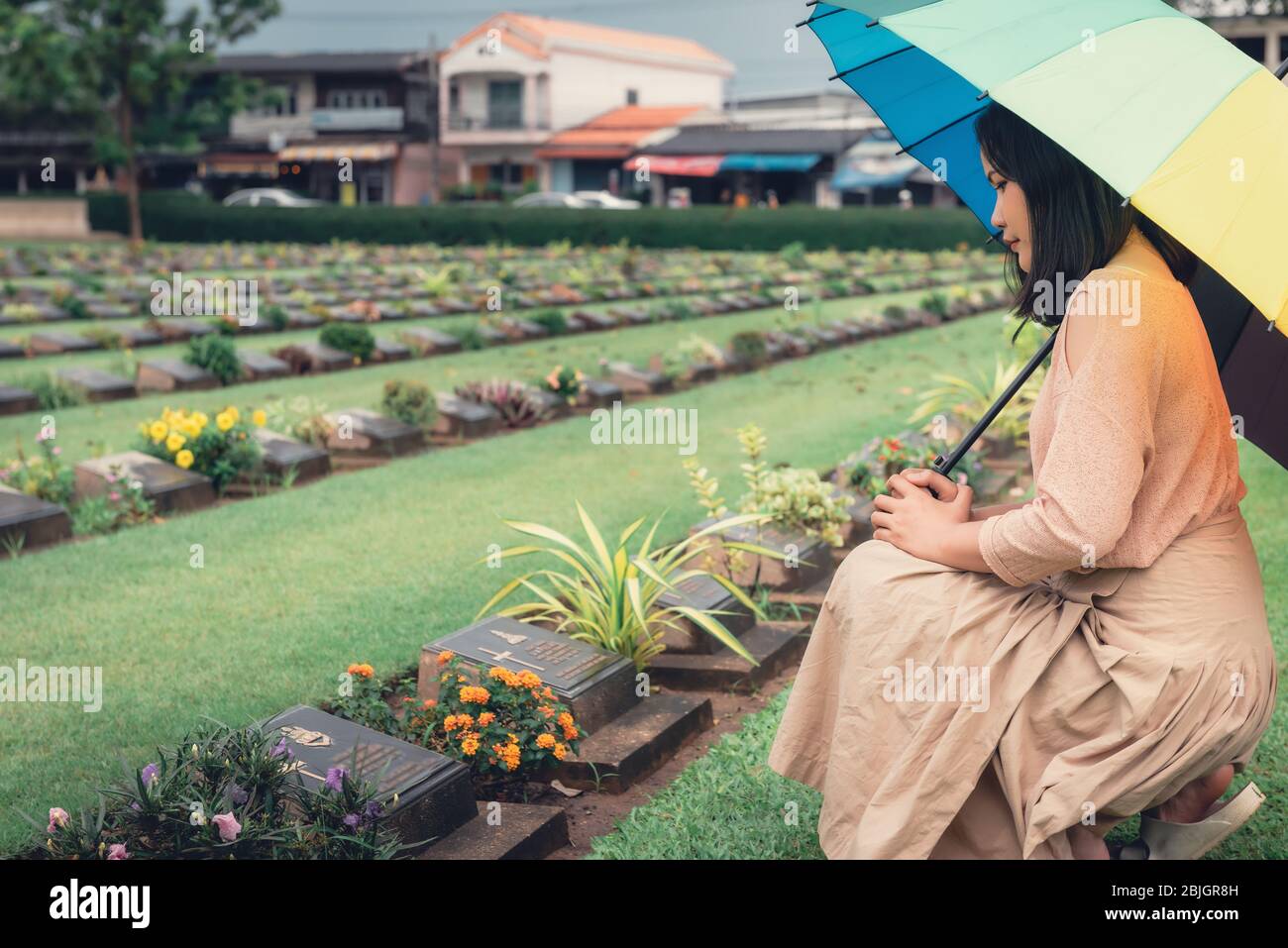 Primo piano di mani religiose cristiane si aggraagliano mentre onorano e pregano i militari nel cimitero di guerra. Donna adolescente in espressione tristezza e P. Foto Stock