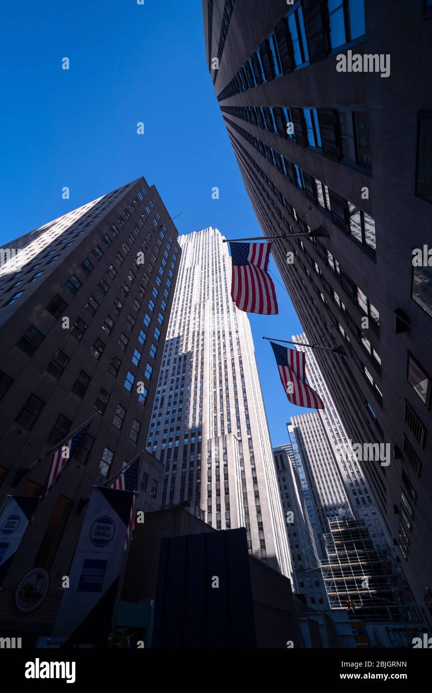 Bandiere americane che guardano sui grattacieli art deco al Rockefeller Center a New York City Foto Stock