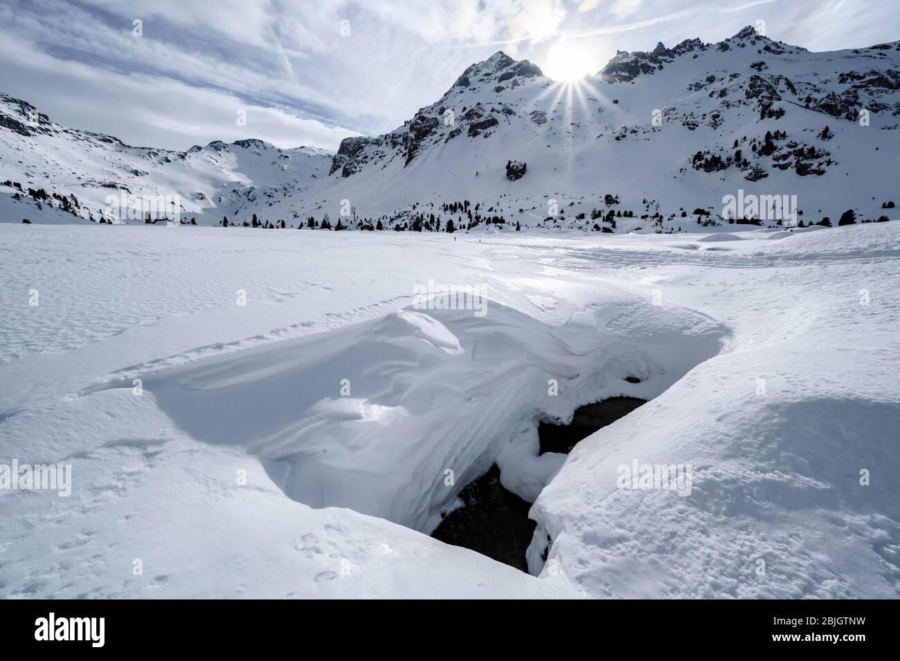 Il sole splende su cime innevate, cime delle gole e teste della Valle del Tarn, copertura di neve aperta davanti a un ruscello che scorre sotto Foto Stock