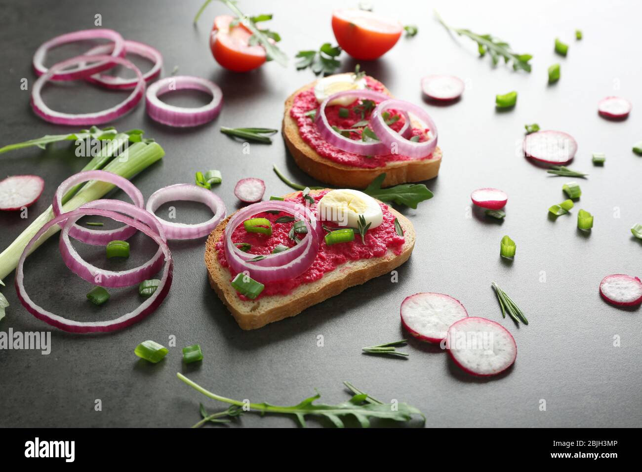 Deliziosi toast piccanti con cipolla e uova su tavola scura Foto Stock