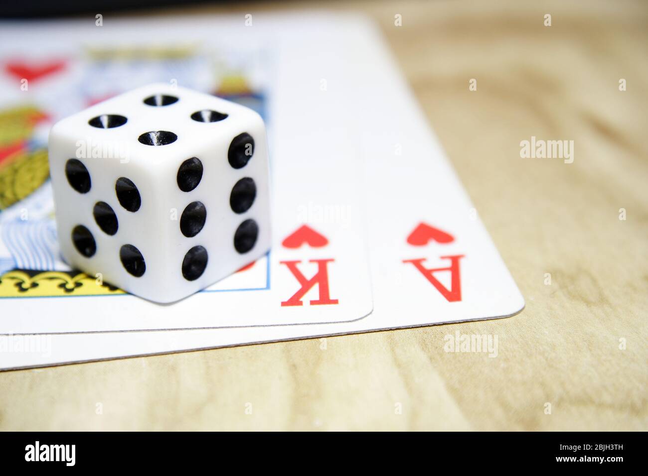 Dadi e carte da gioco su un tavolo di pino che mostra Black Jack con Re e Asso dei cuori. Foto Stock