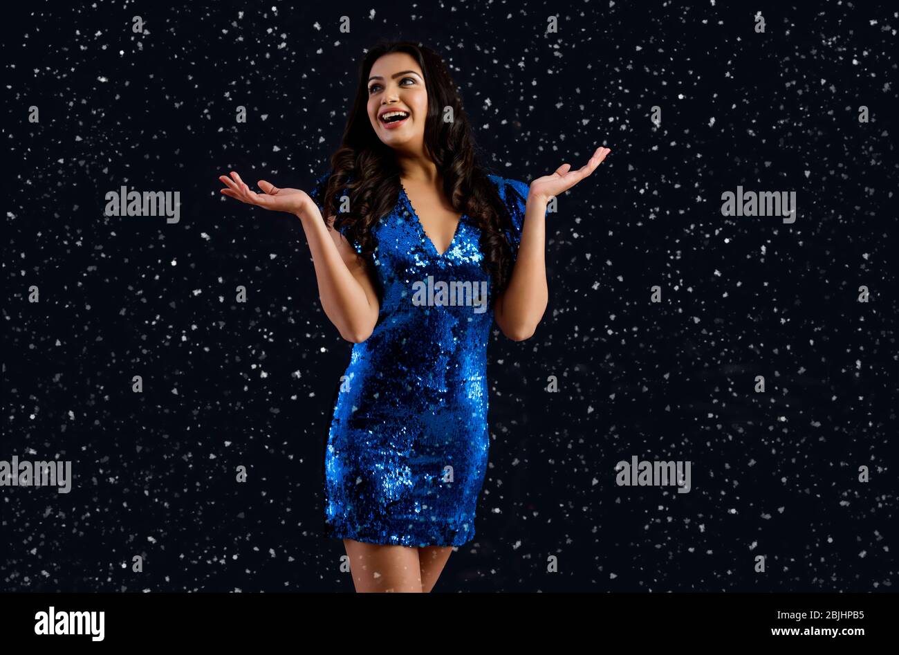 Giovane donna che guarda sbalordiosamente a luccica intorno a lei a un nuovo anno partito. Foto Stock