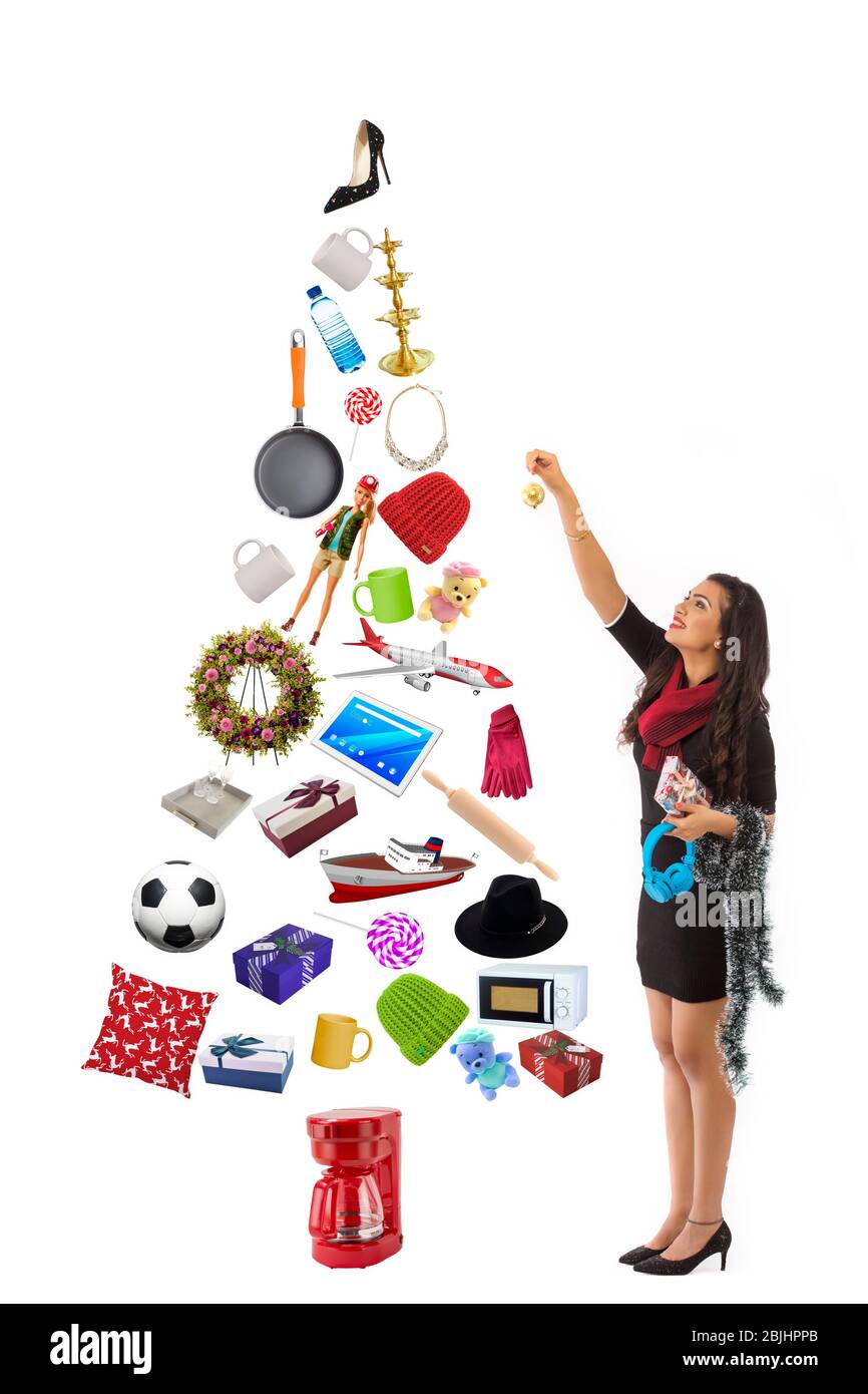 Giovane donna che decora un albero di Natale fatto con i regali. Foto Stock