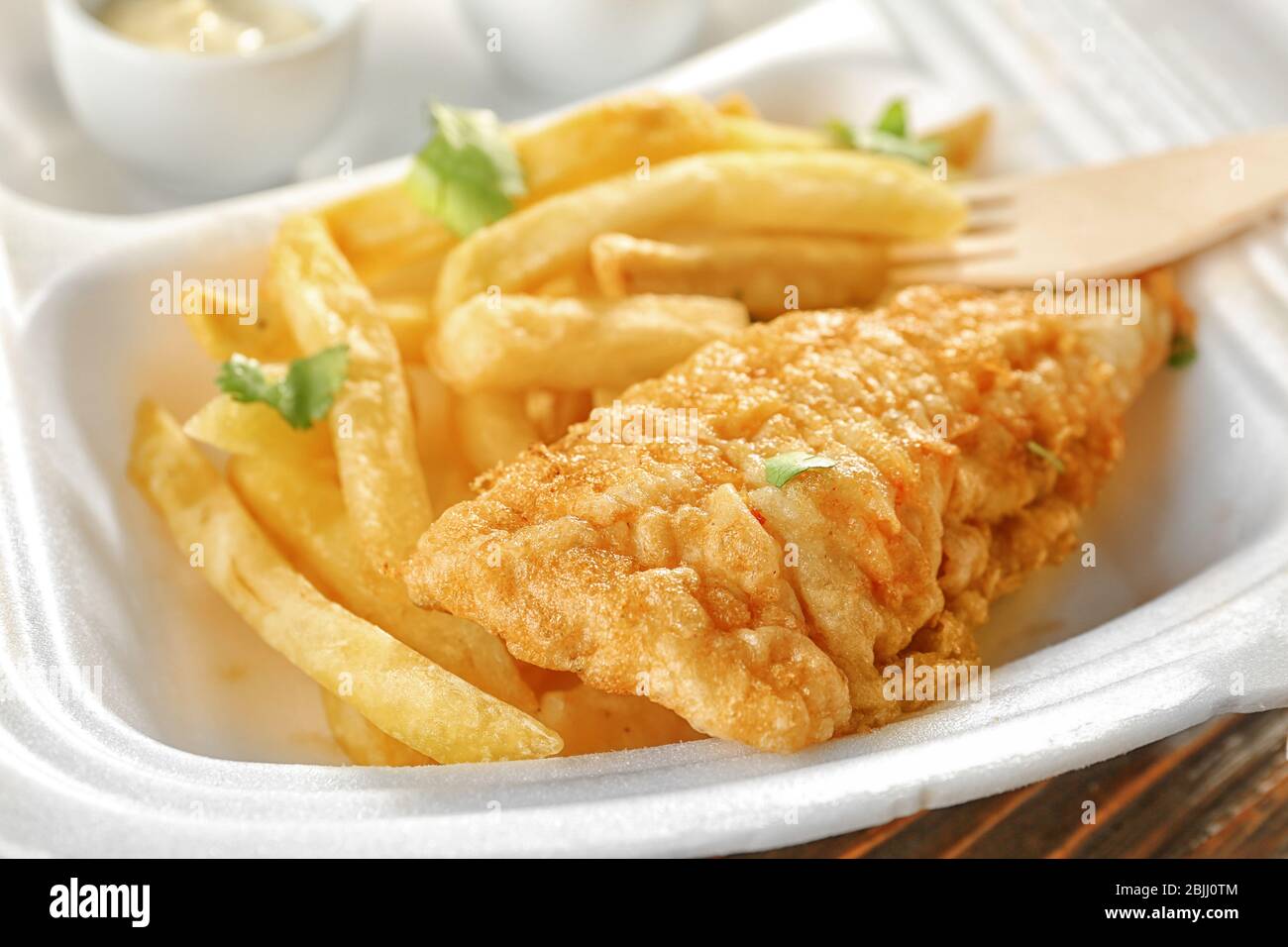 Gustosi patatine fritte di pesce e patatine fritte in un pranzo al tavolo, primo piano Foto Stock