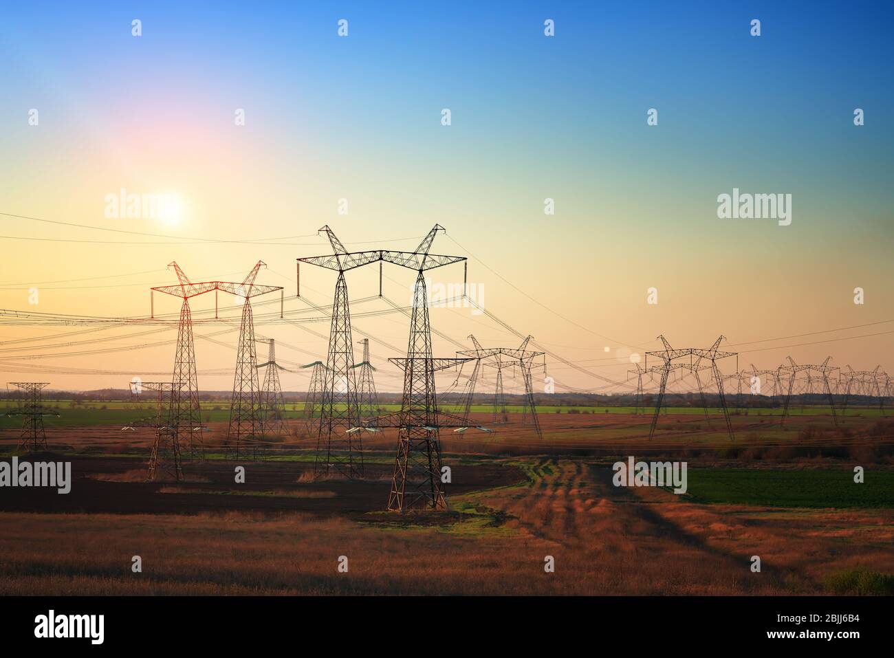 Torre elettrica ad alta tensione al tramonto. Tramonto cielo sfondo. Torre di alimentazione Foto Stock