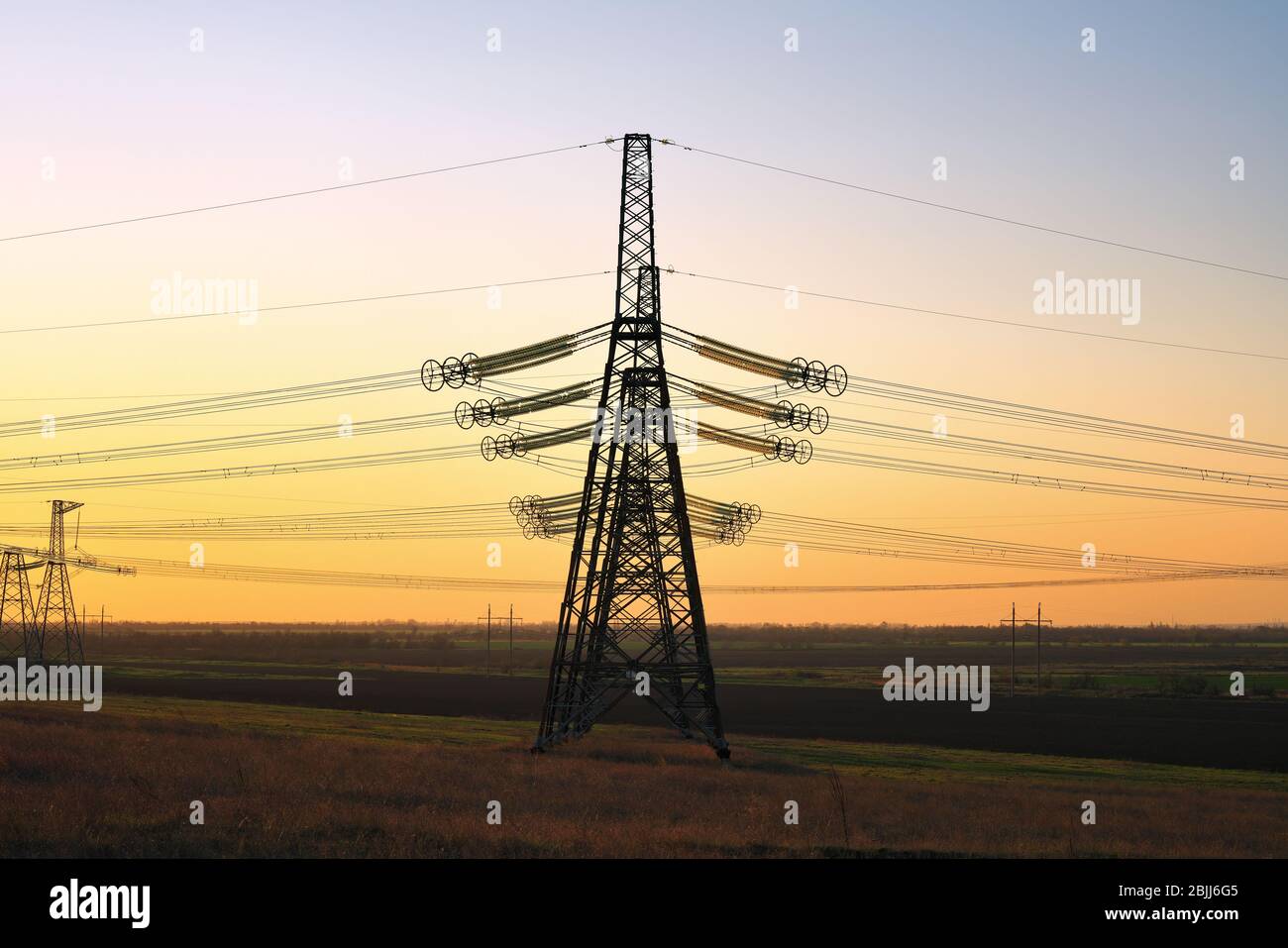 Torre elettrica ad alta tensione al tramonto. Tramonto cielo sfondo. Torre di alimentazione Foto Stock