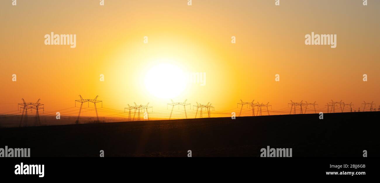 Torre elettrica ad alta tensione sul panorama del tramonto. Sfondo del cielo del tramonto. Torre di alimentazione Foto Stock