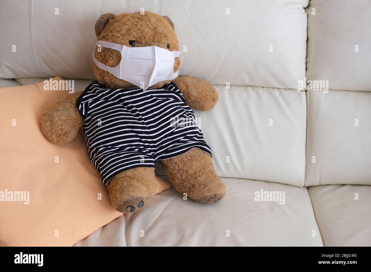 orso di teddy su un divano con maschera per evitare il coronavirus Foto Stock