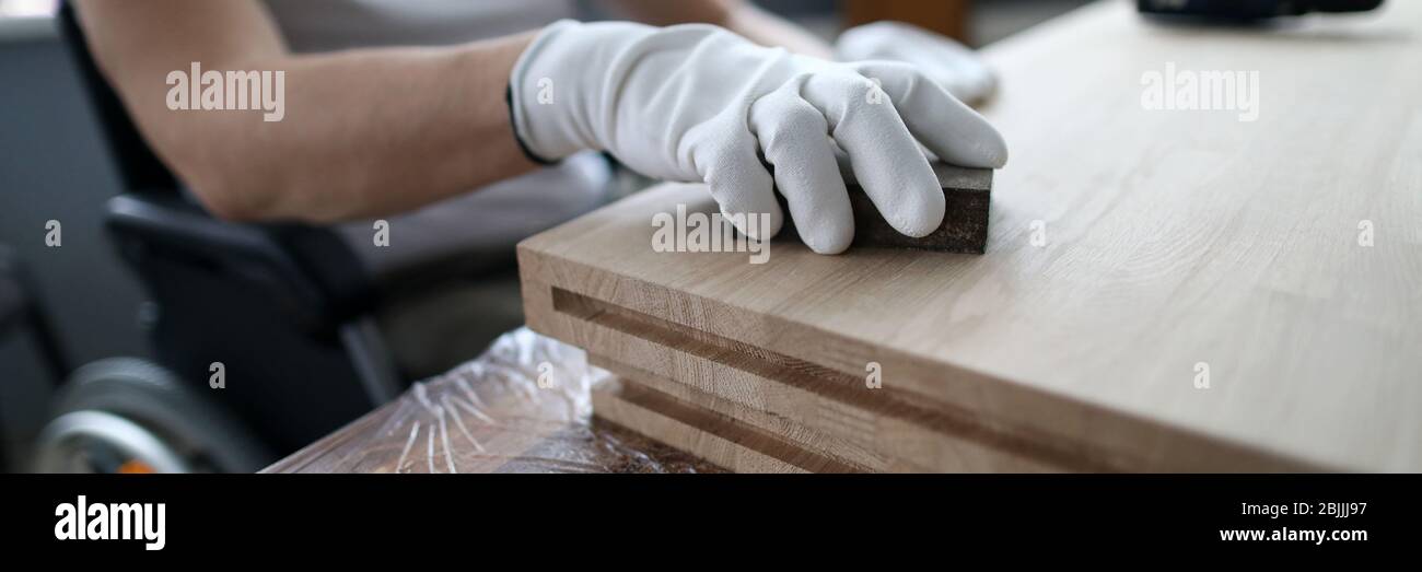 L'uomo siede su una sedia a rotelle e lavora come falegname Foto Stock