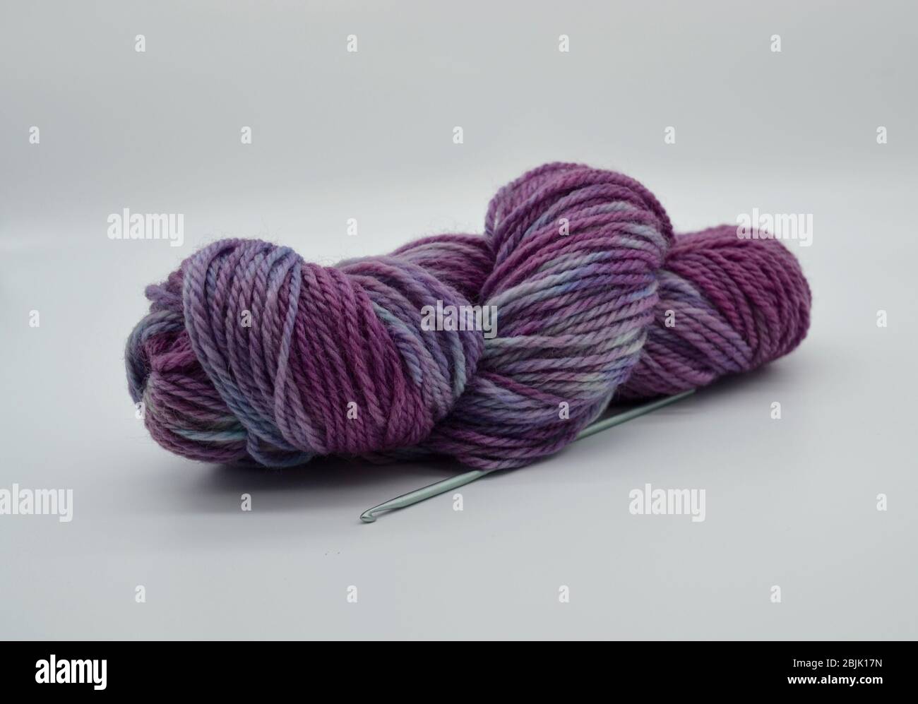 Matassa o palla di lana o filato viola tinto a mano e filato a mano in studio girato con sfondo bianco Foto Stock