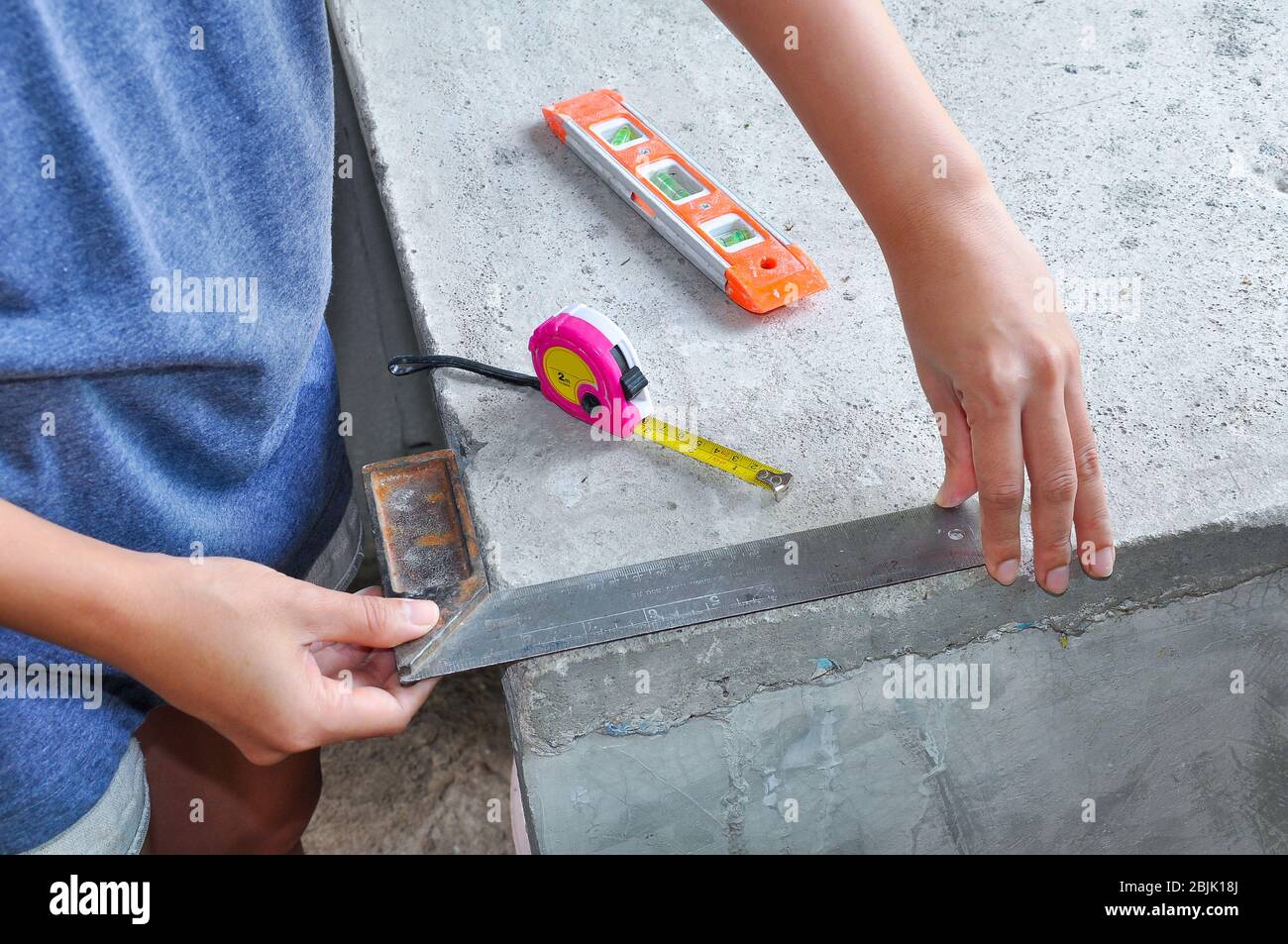 il meccanico utilizza l'attrezzo ad angolo retto sul calcestruzzo Foto Stock