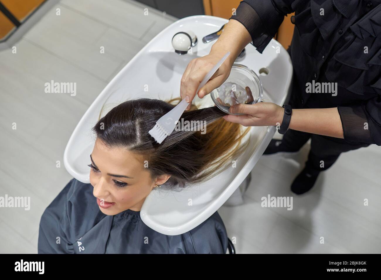 Estetista che effettua il trattamento sui capelli della donna, salone di parrucchiere e clinica di bellezza. Foto Stock