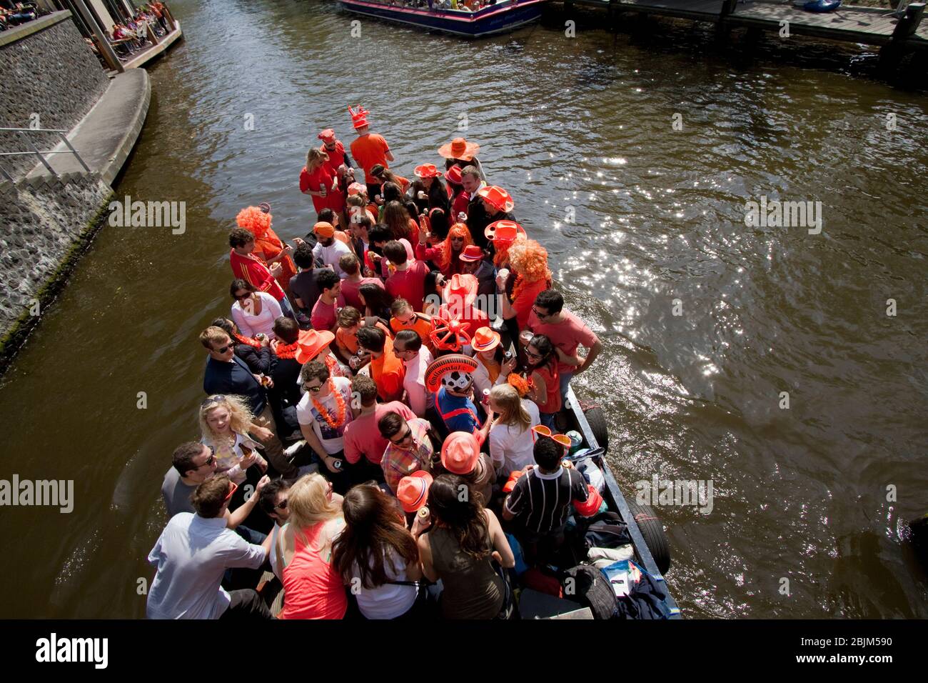 Una barca traboccante di gente gira intorno ai canali di Amsterdam durante le celebrazioni per il giorno del giorno di festa 2014. Foto Stock