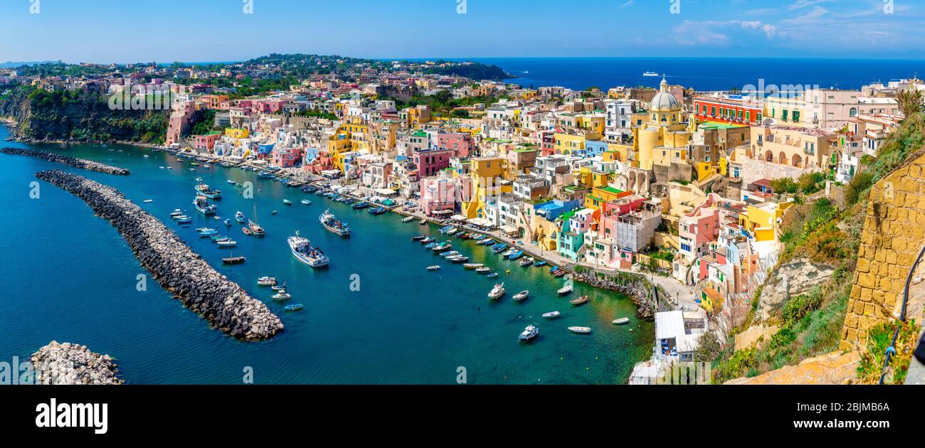Vista panoramica sulle case colorate e sul porto del villaggio di Corricella sull'isola di Procida in una giornata estiva di sole, Napoli, Italia Foto Stock