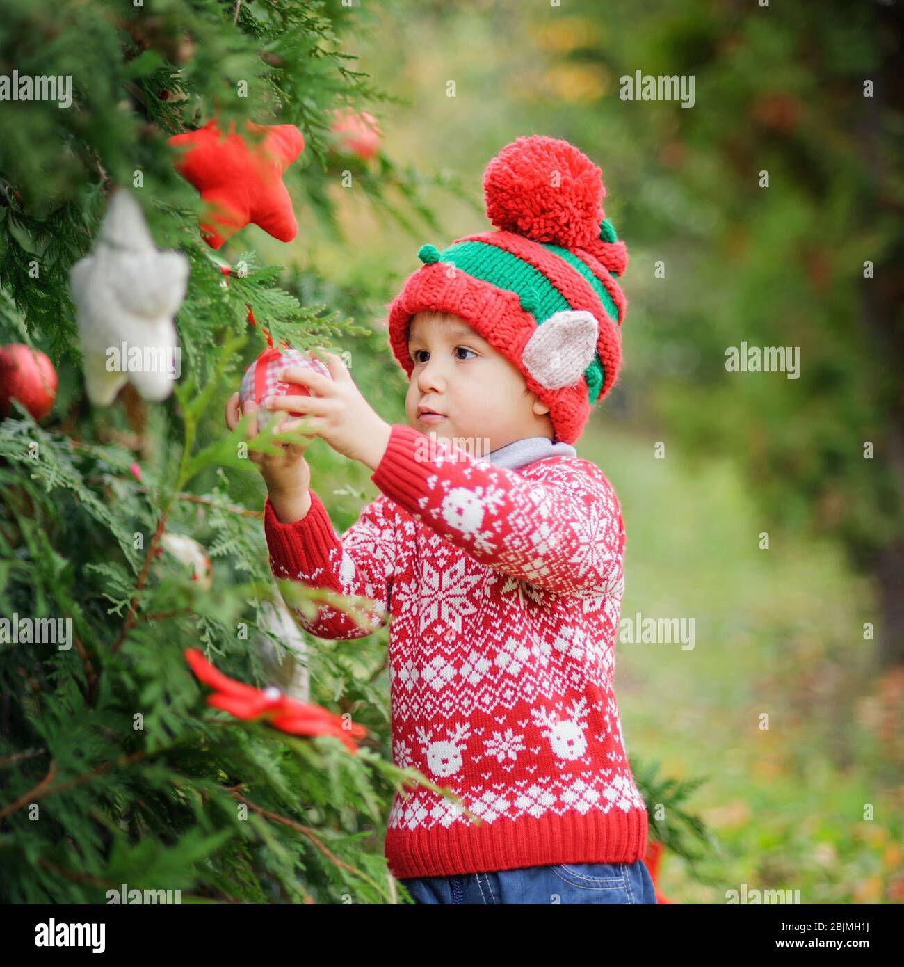 Bambino in attesa di Natale in legno. Ritratto del ragazzino vicino albero di natale. Baby decorazione pino. Vacanze invernali e concetto di persone. Allegro Chris Foto Stock