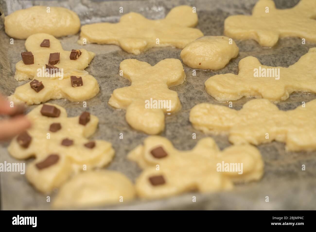 biscotti fatti in casa a forma di uomini su una teglia prima di cuocere Foto Stock