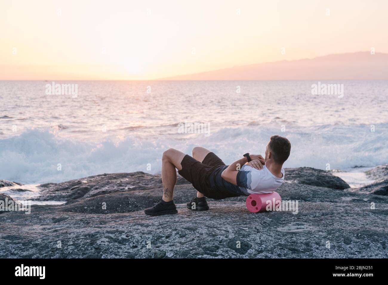Uomo che fa auto massaggio del corpo con un rotolo. Formazione fascia Foto Stock