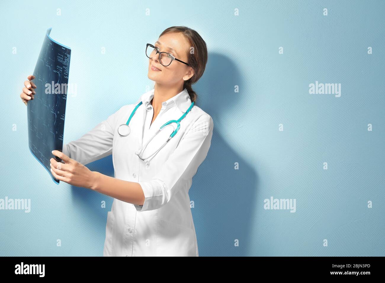 Medico femminile con immagine a raggi X su sfondo chiaro Foto Stock