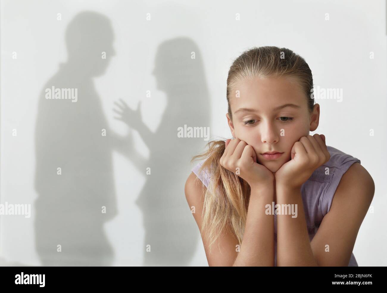 Bambina e silhouette di genitori litigiosi sullo sfondo. Concetto di violenza domestica Foto Stock