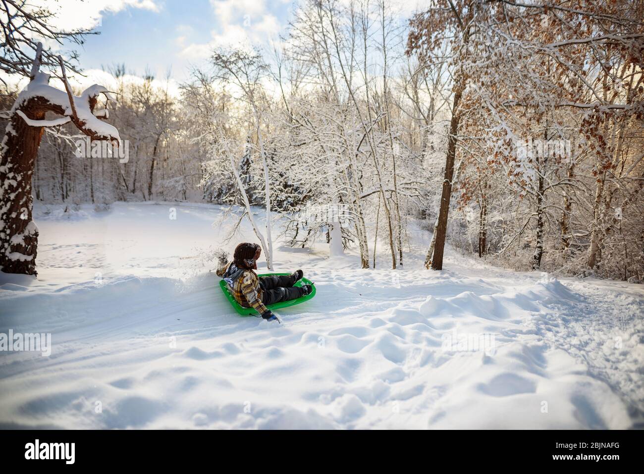 Ragazzo che slitta giù una collina nella neve, USA Foto Stock