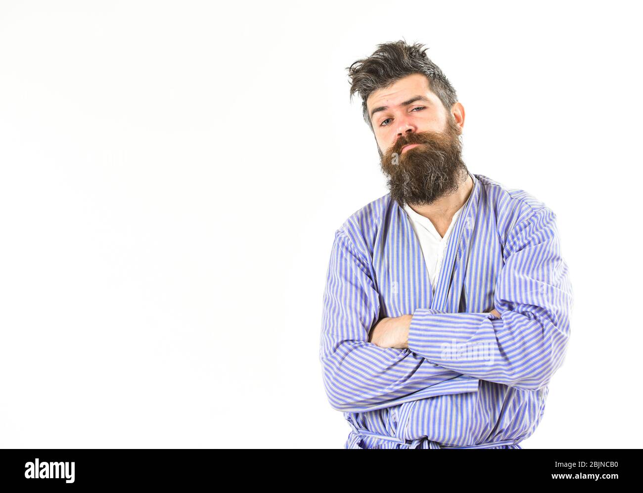 Concetto di sonno male. Il ragazzo tiene le mani incrociate sul petto, spazio per le copie. Il nasello con barba e baffi con capelli capienti indossa un accappatoio. Uomo con faccia sonnolenta su sfondo bianco. Foto Stock