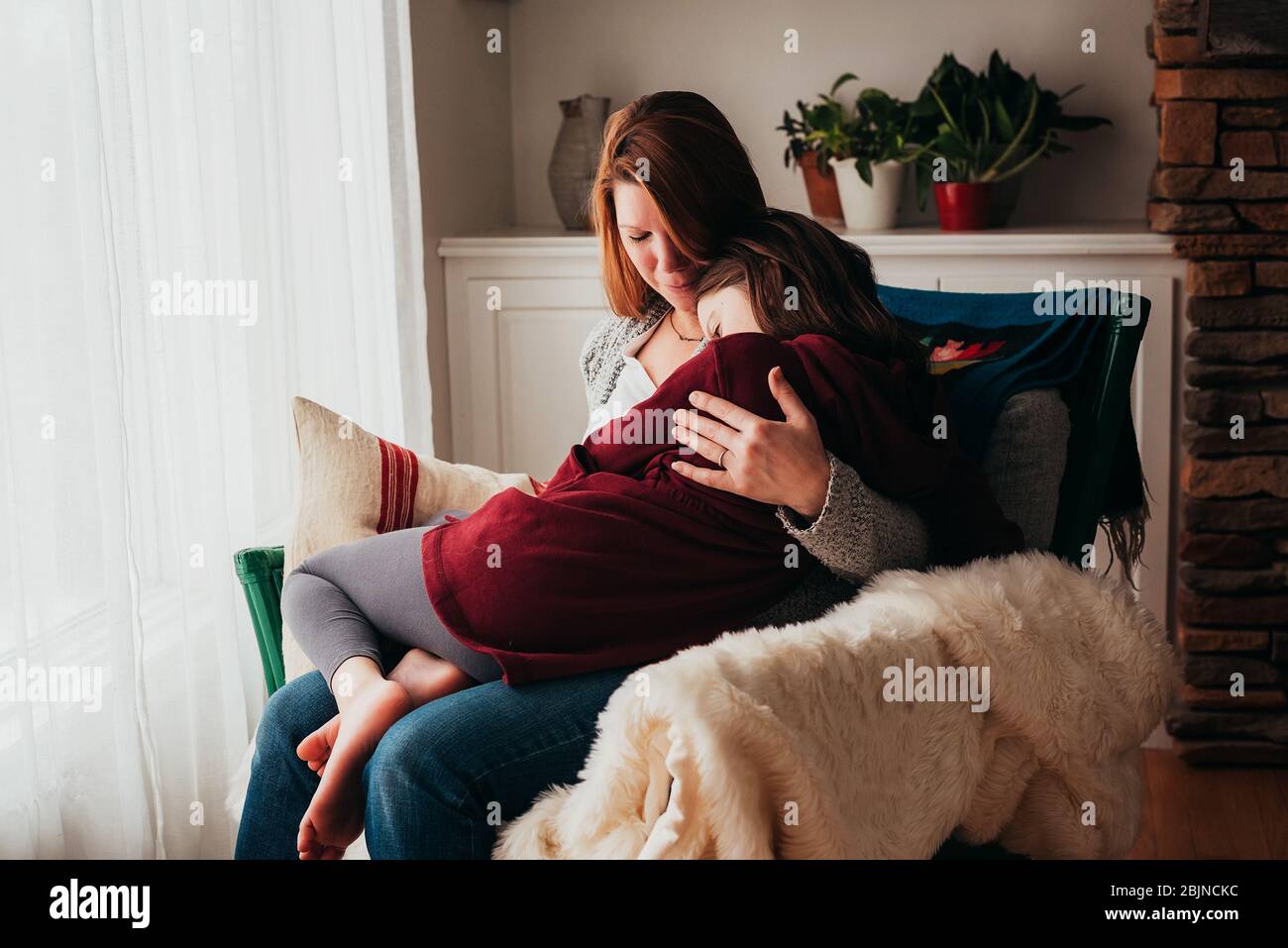 Ragazza seduta in grembo di sua madre Foto Stock