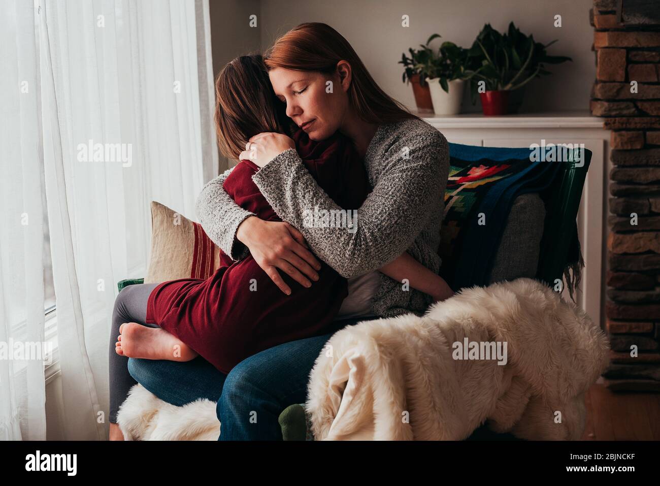 Ragazza seduta sul grembo di sua madre coccolarsi Foto Stock