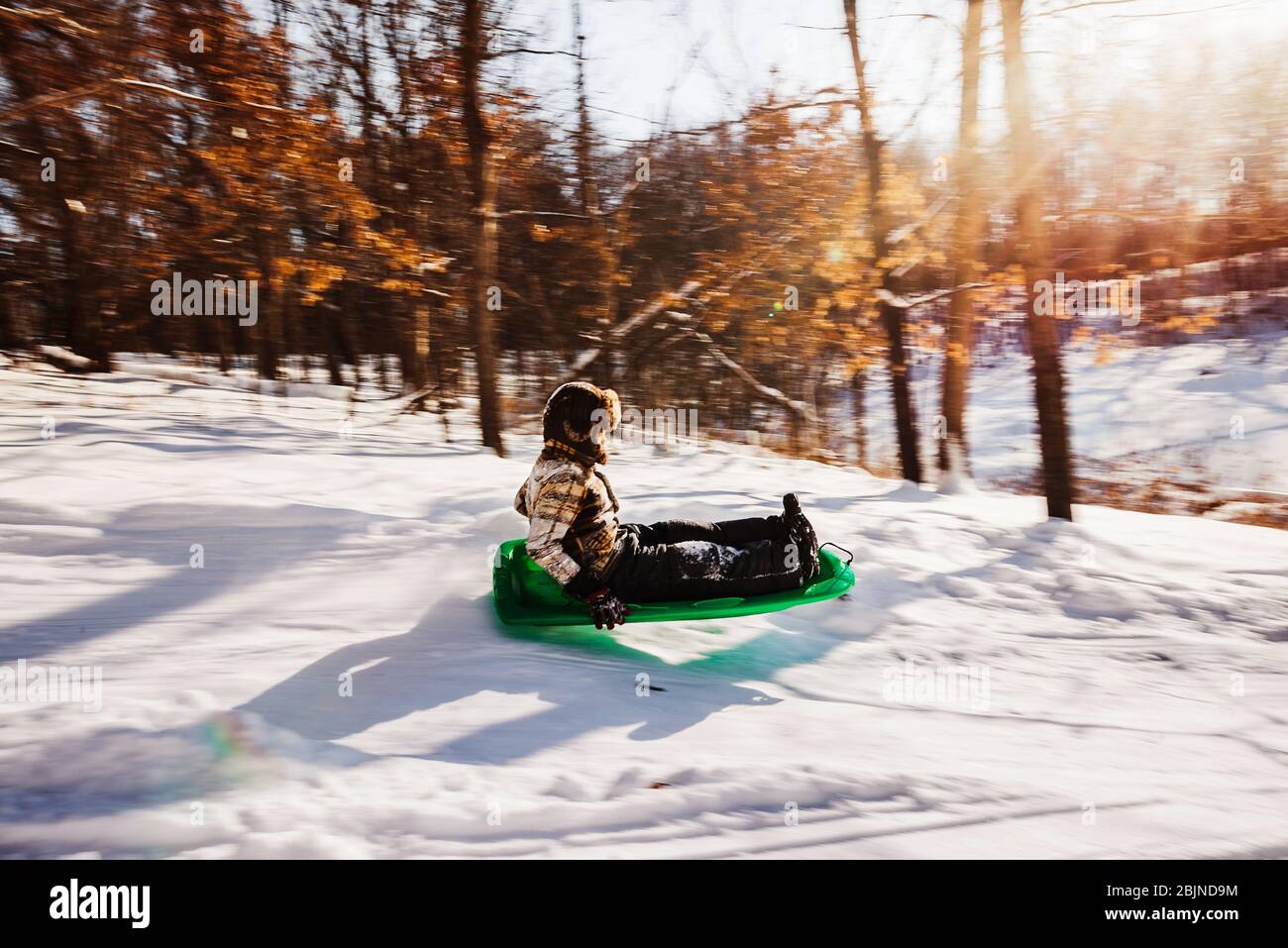 Ragazzo che slitta giù una collina nella neve, USA Foto Stock