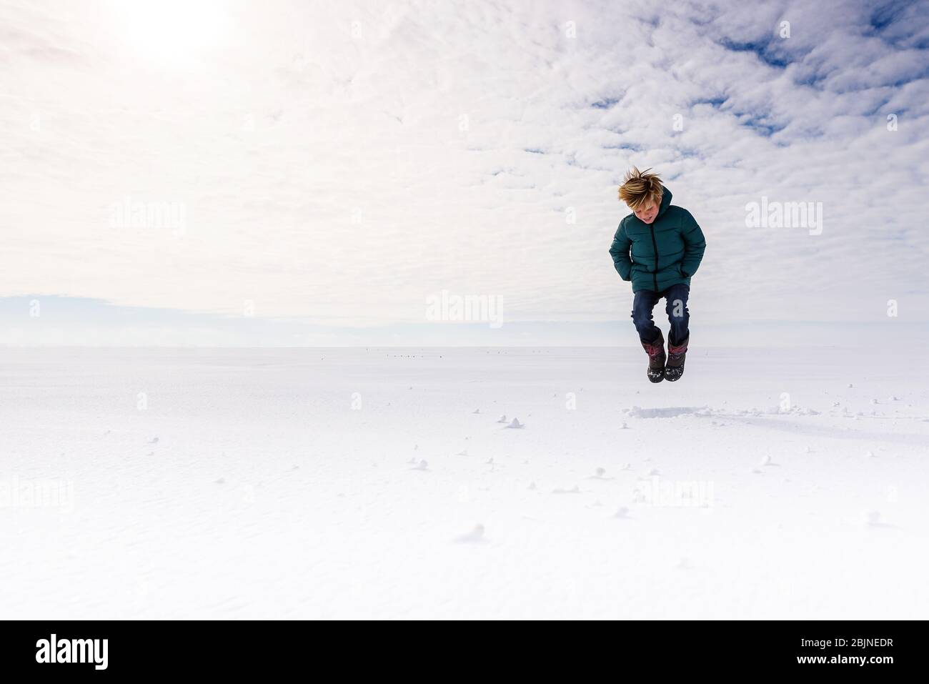 Ragazzo che salta a mezz'aria in un campo nevoso, USA Foto Stock