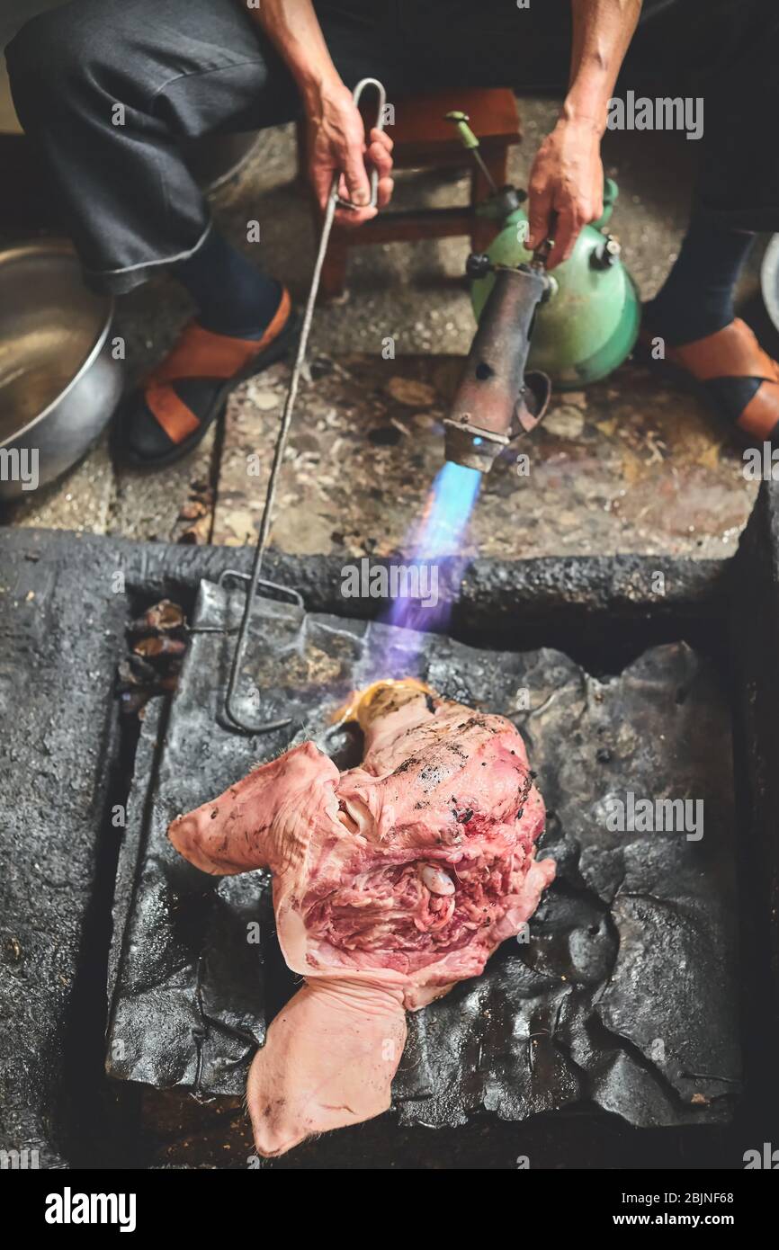 Bruciando fuori i capelli grossolani del porco al mercato locale, fuoco selettivo, Cina. Foto Stock
