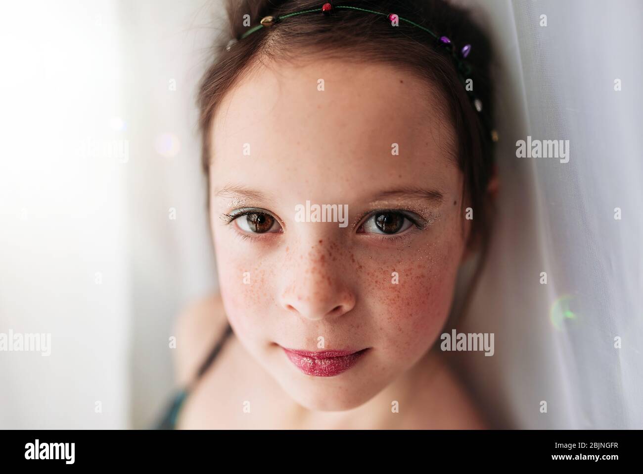 Ritratto di una ragazza giovane che indossa make-up in piedi da una tenda Foto Stock