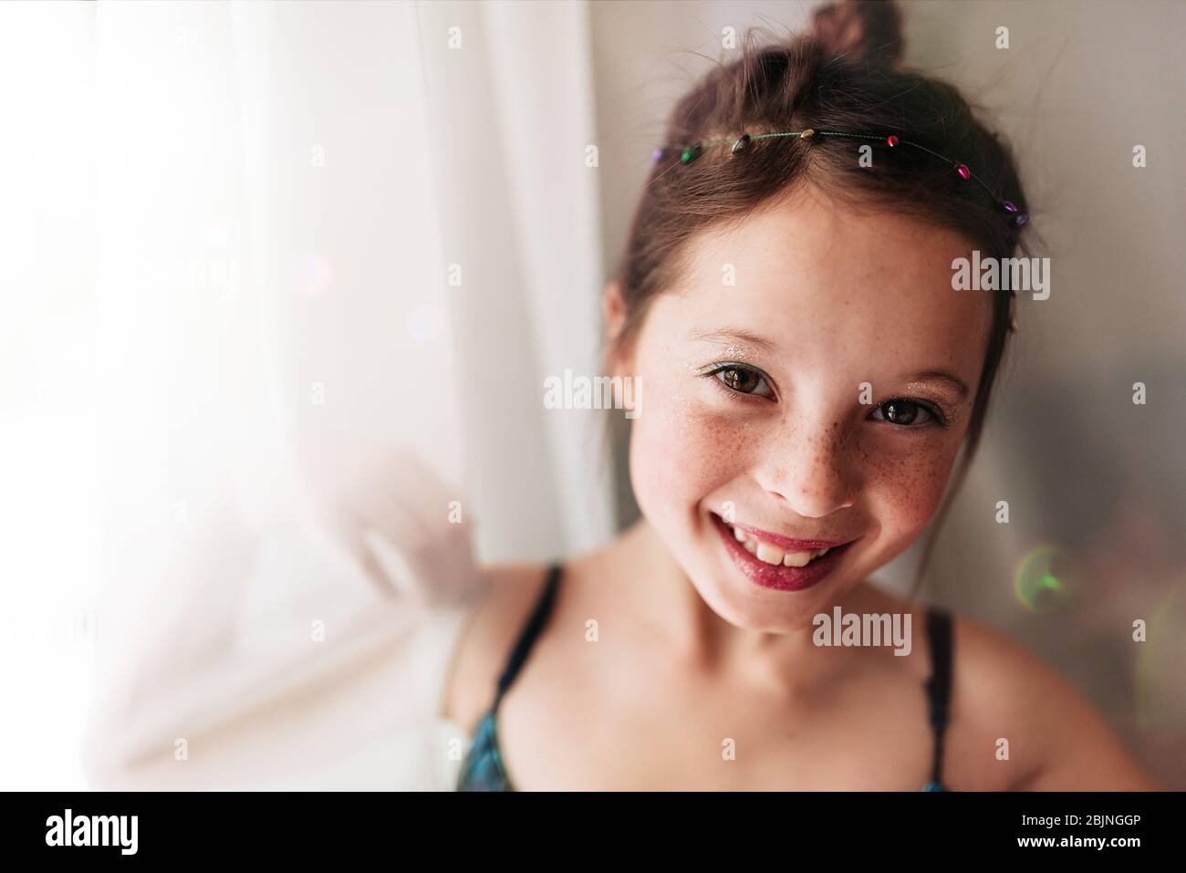 Ritratto di una ragazza giovane che indossa make-up in piedi da una tenda Foto Stock