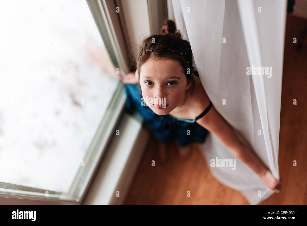 Vista dall'alto di una ragazza in piedi da una finestra Foto Stock