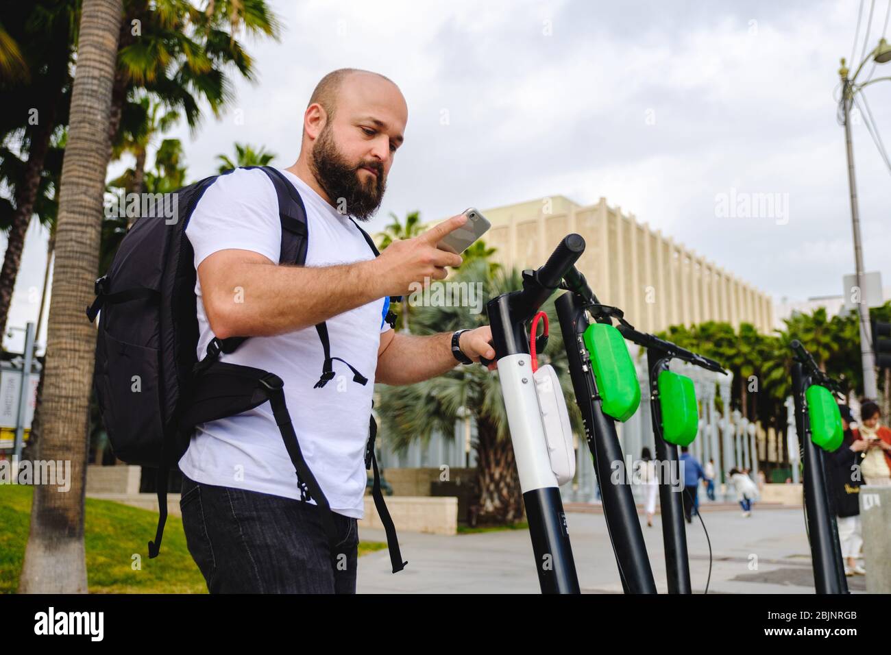 Giovane uomo che scansiona il codice qr con il suo telefono per il noleggio di scooter elettrico. Foto Stock