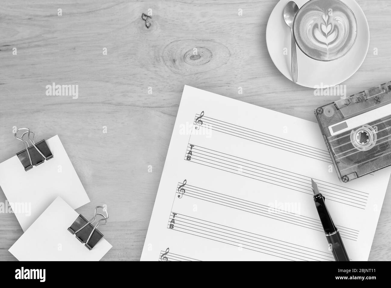 Musica da foglio, penna stilografica, cassetta a nastro e caffè in latte su tavolo di legno, foto vista dall'alto Foto Stock