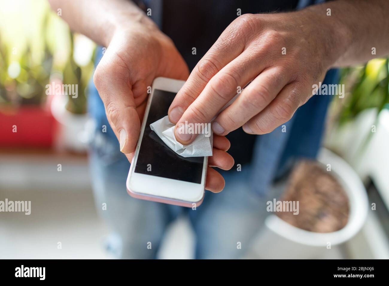 Uomo che utilizza un panno disinfettante su un telefono Foto Stock