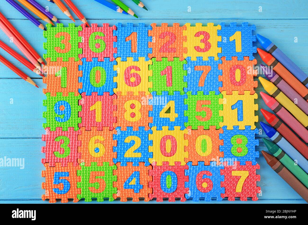 Puzzle matematico, matite e pastelli su sfondo blu Foto Stock
