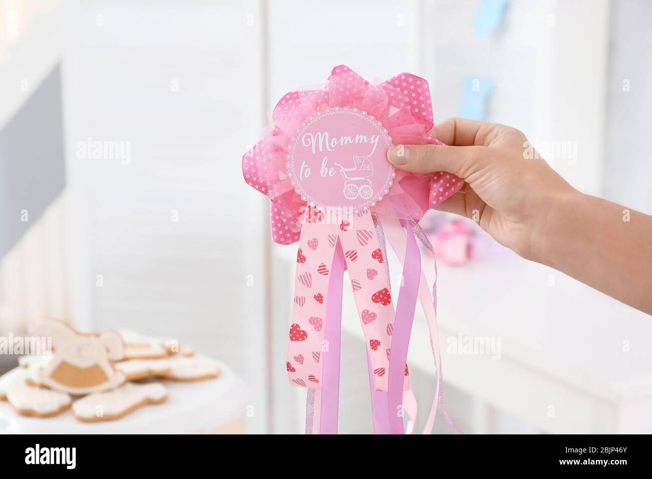 Donna che tiene nastro premio con il testo MUMMY PER ESSERE su sfondo sfocato Foto Stock