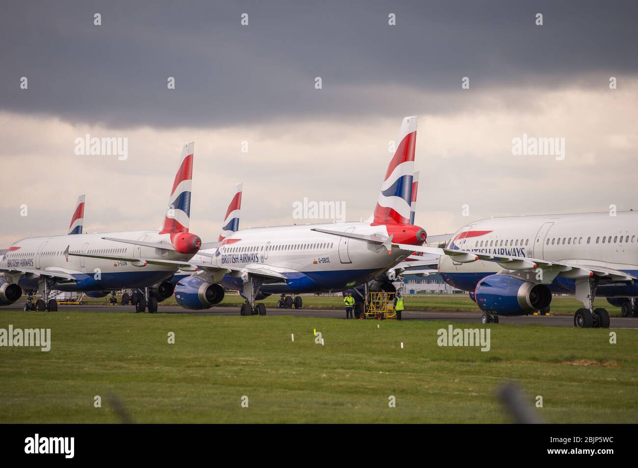 Glasgow, Regno Unito. 30 Aprile 2020. Nella foto: Le nuvole tempesta si riuniscono mentre gli equipaggi di terra della British Airways assistono alla raccolta di 14 aeromobili Airbus A319/A320 e A321 collegati a terra che sono stati parcheggiati sulla seconda pista dell'aeroporto di Glasgow dall'inizio del blocco Coronavirus (COVID-19). Da allora, l'industria globale delle compagnie aeree è andata in tracollo con alcune compagnie aeree che vanno in fallimento e altre come BA che chiedono assistenza finanziaria al governo. Ad oggi BA ha annunciato che è axing quasi 12,000 personale. Credit: Colin Fisher/Alamy Live News Foto Stock