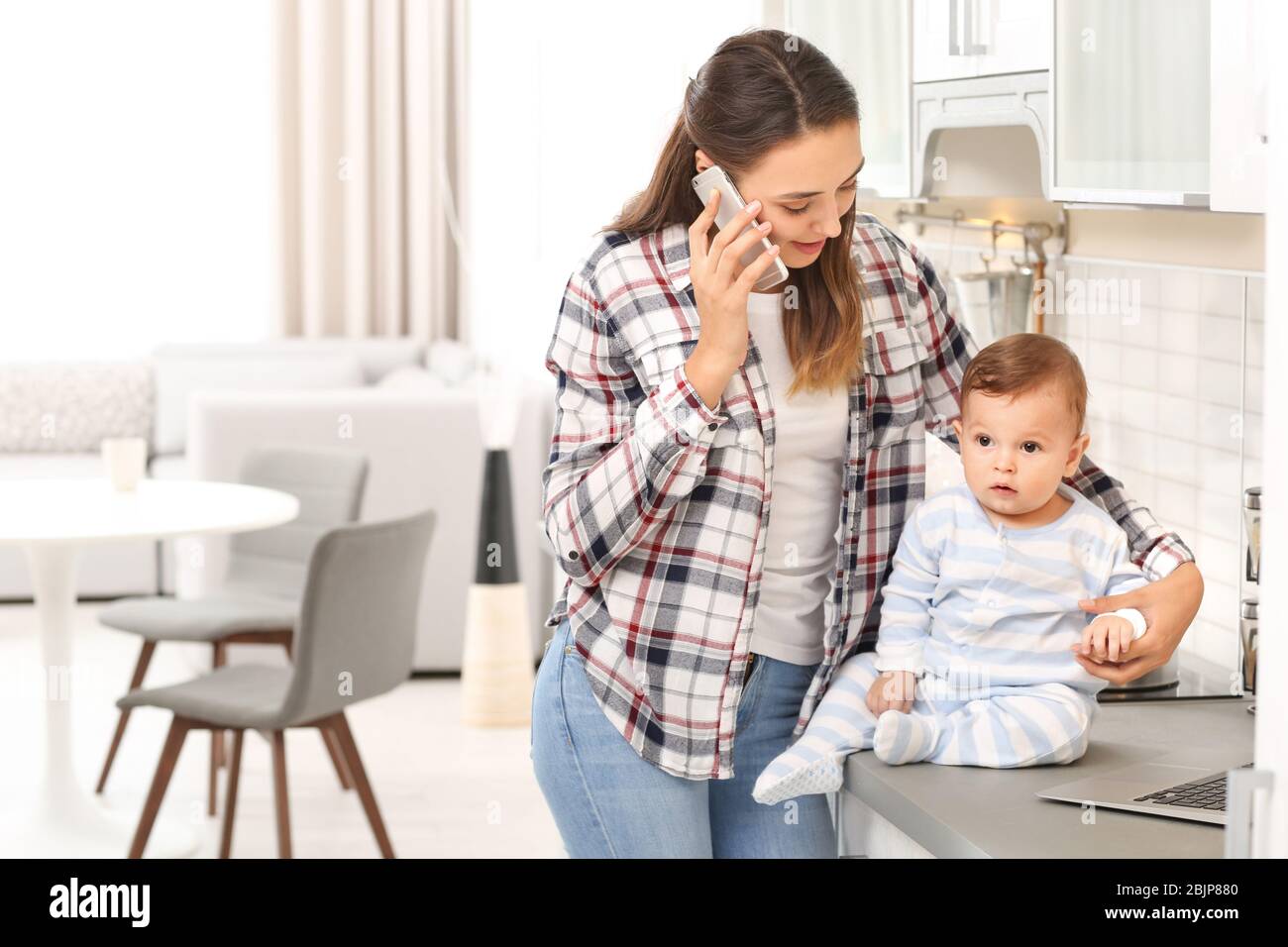 Giovane donna con bambino che lavora in casa Foto Stock