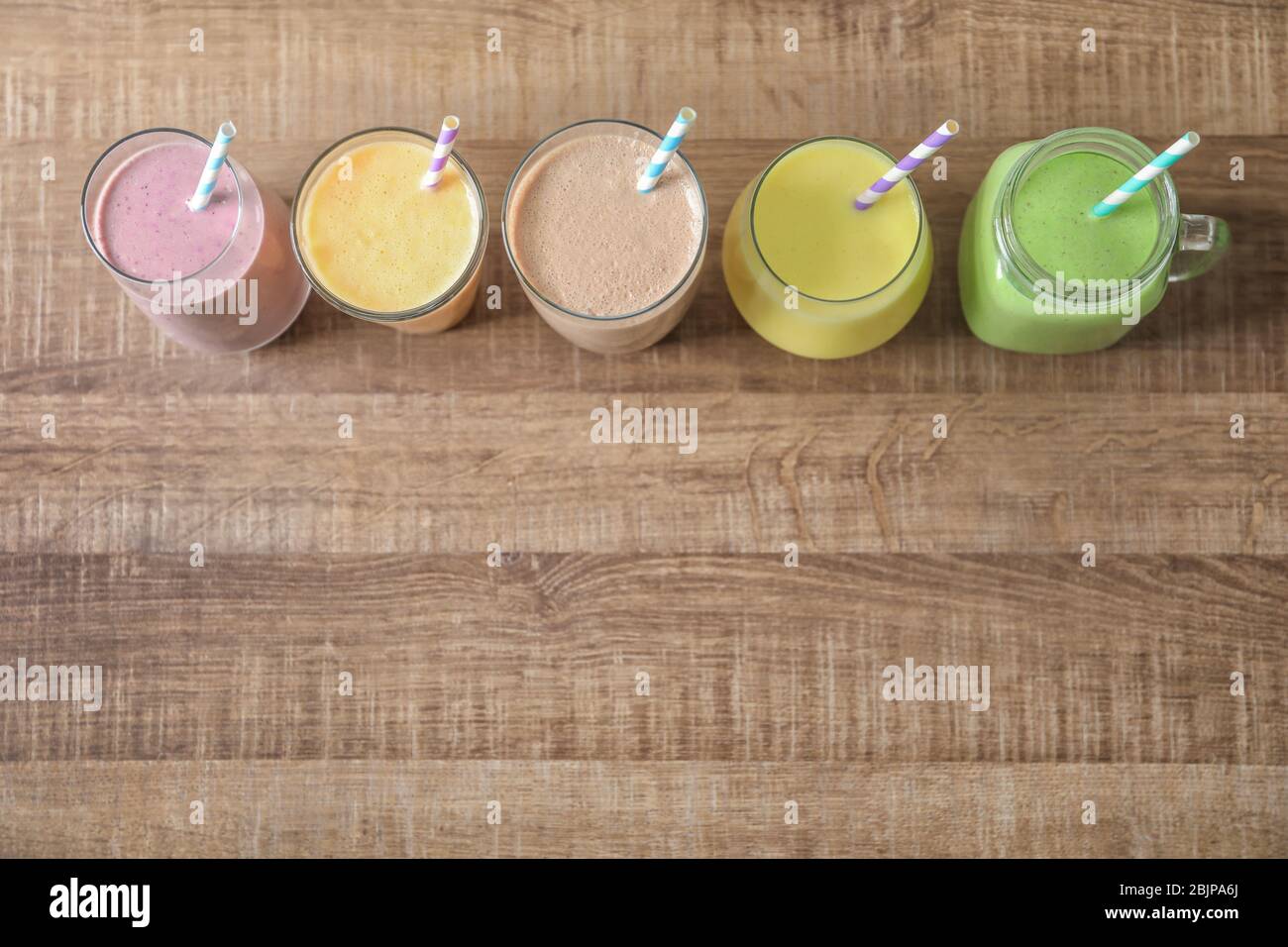 Diversi milkshake in vetreria su sfondo di legno Foto Stock