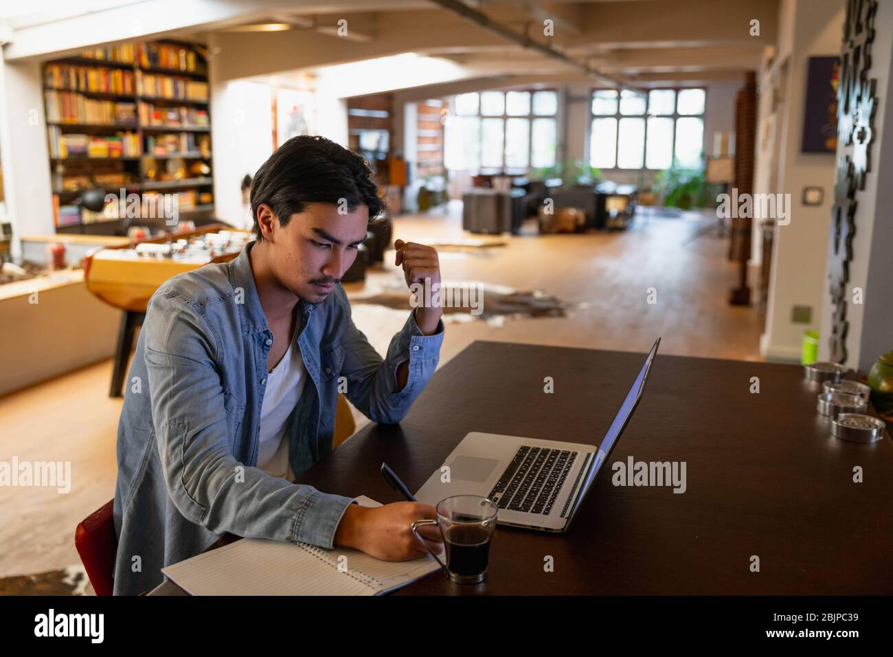 Giovane uomo che lavora a casa sul suo notebook Foto Stock