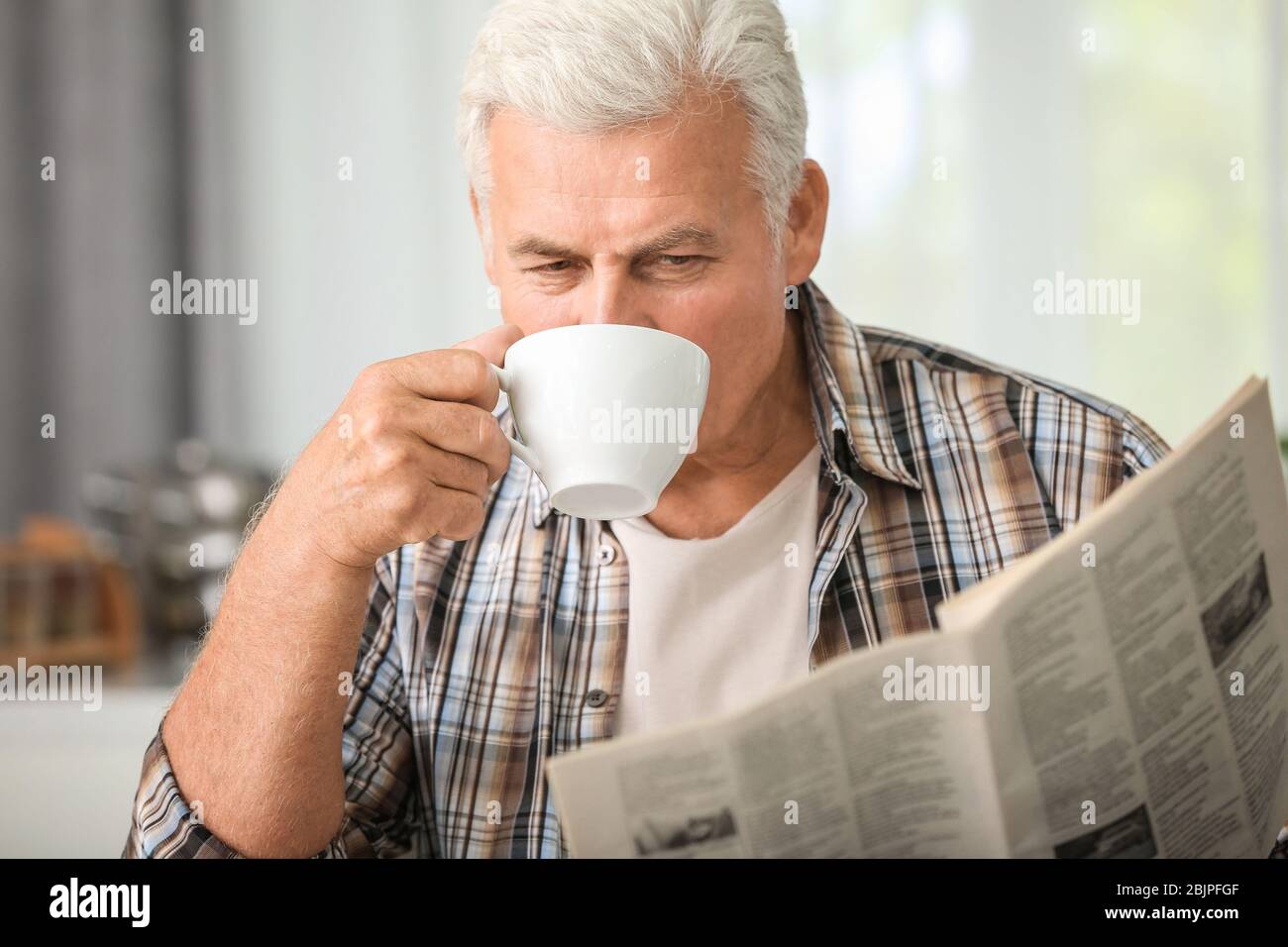 Bel giornale maturo lettura uomo in cucina Foto Stock