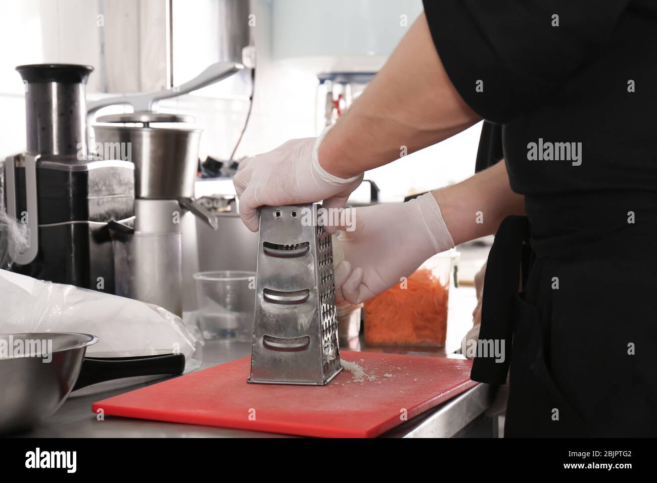Chef maschio grattugiare formaggio in cucina ristorante, primo piano Foto Stock