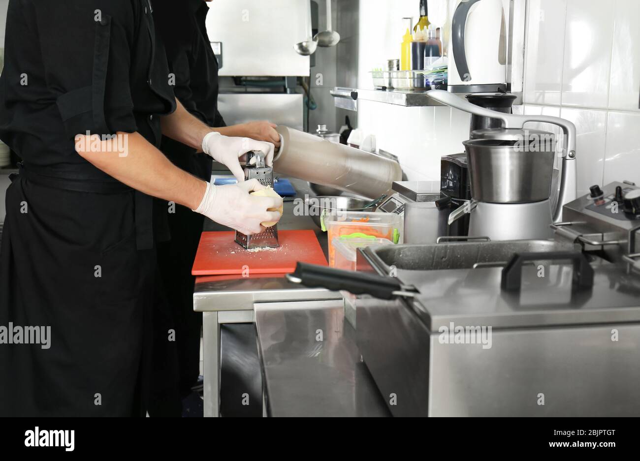 Chef maschile che grattugiano il formaggio nella cucina del ristorante Foto Stock