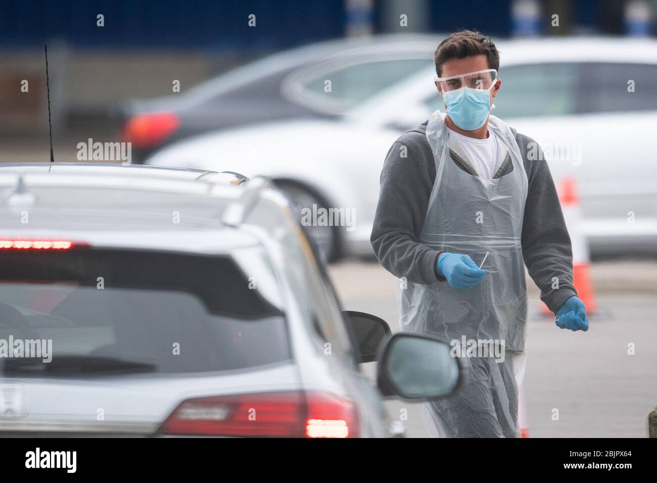 Un tester che indossa dispositivi di protezione individuale (PPE) tiene un tampone di prova in un viaggio attraverso il sito di test per coronavirus presso IKEA a Wembley, a nord di Londra. Foto Stock