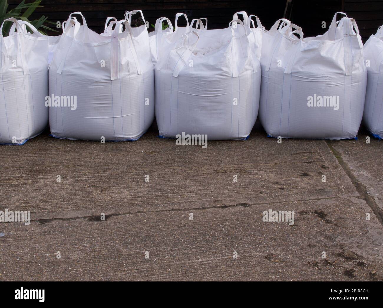 Fila di sacchi di sabbia bianca con cemento in primo piano Foto Stock
