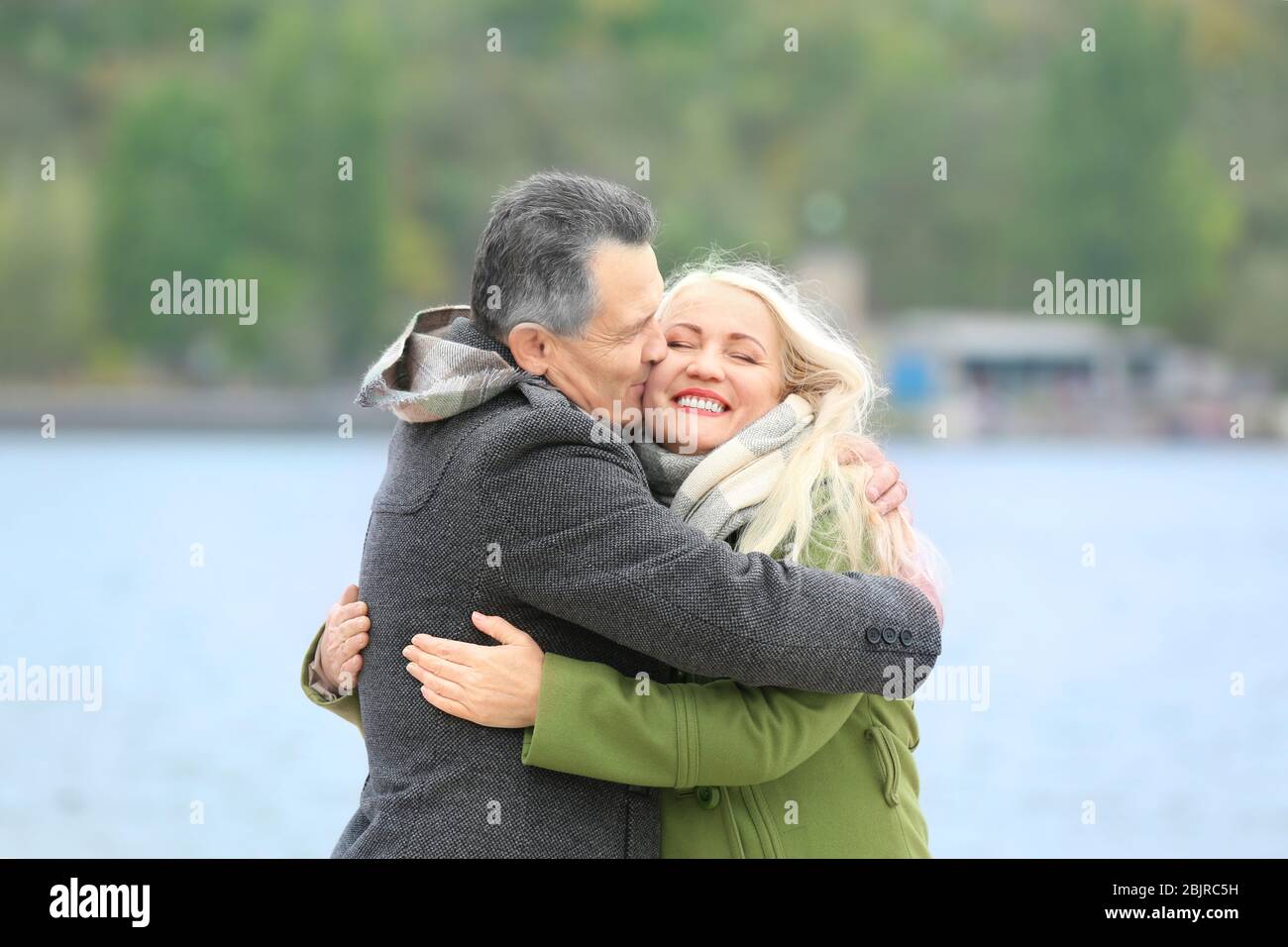 Felice coppia matura abbracciando sul lungofiume Foto Stock