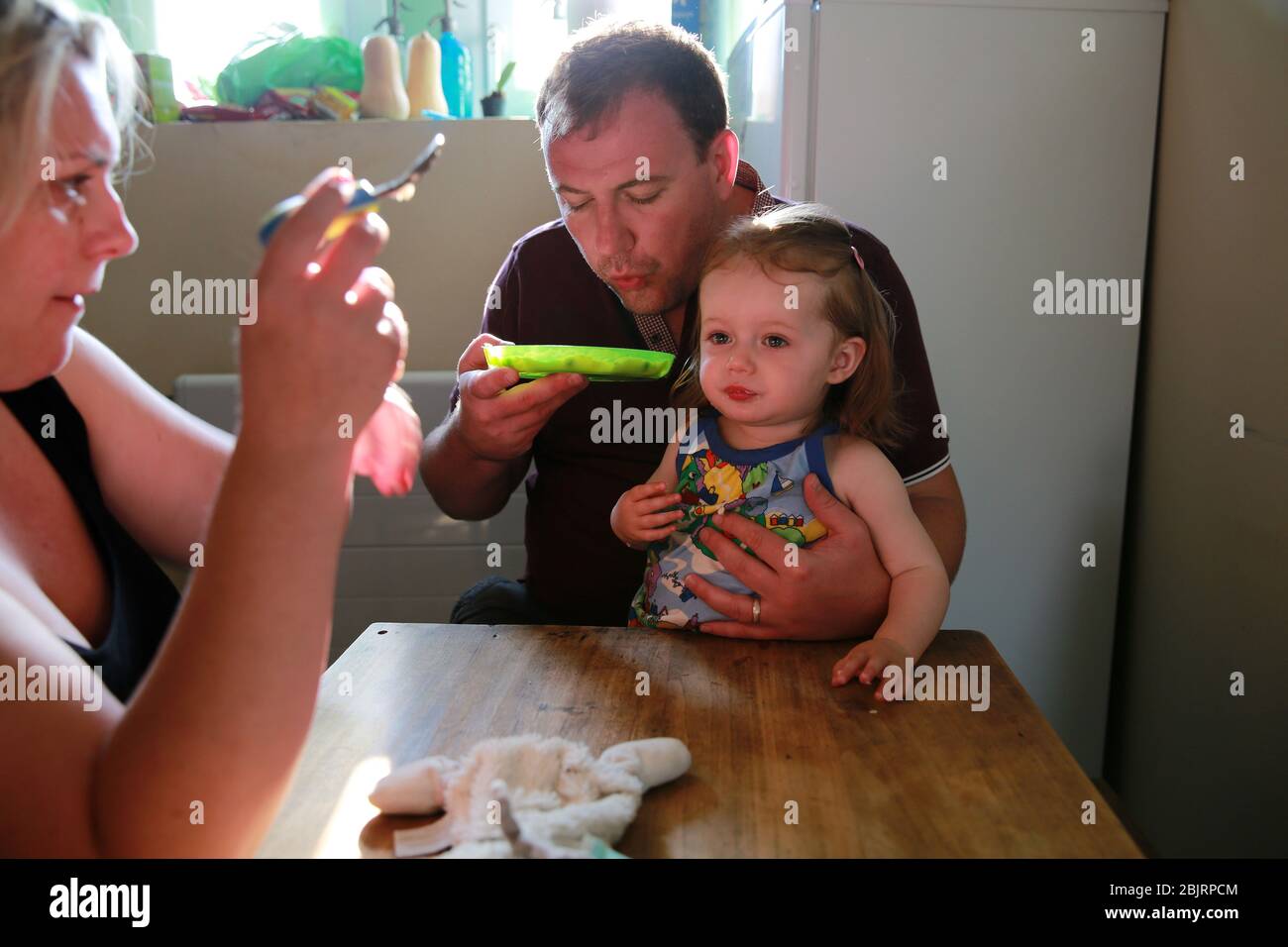Mamma e papà nutrono il loro bambino in casa. Foto Stock